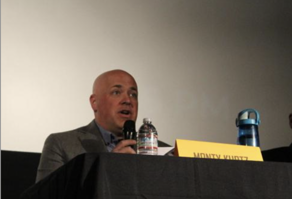 Candidates speaking into microphones at forum.