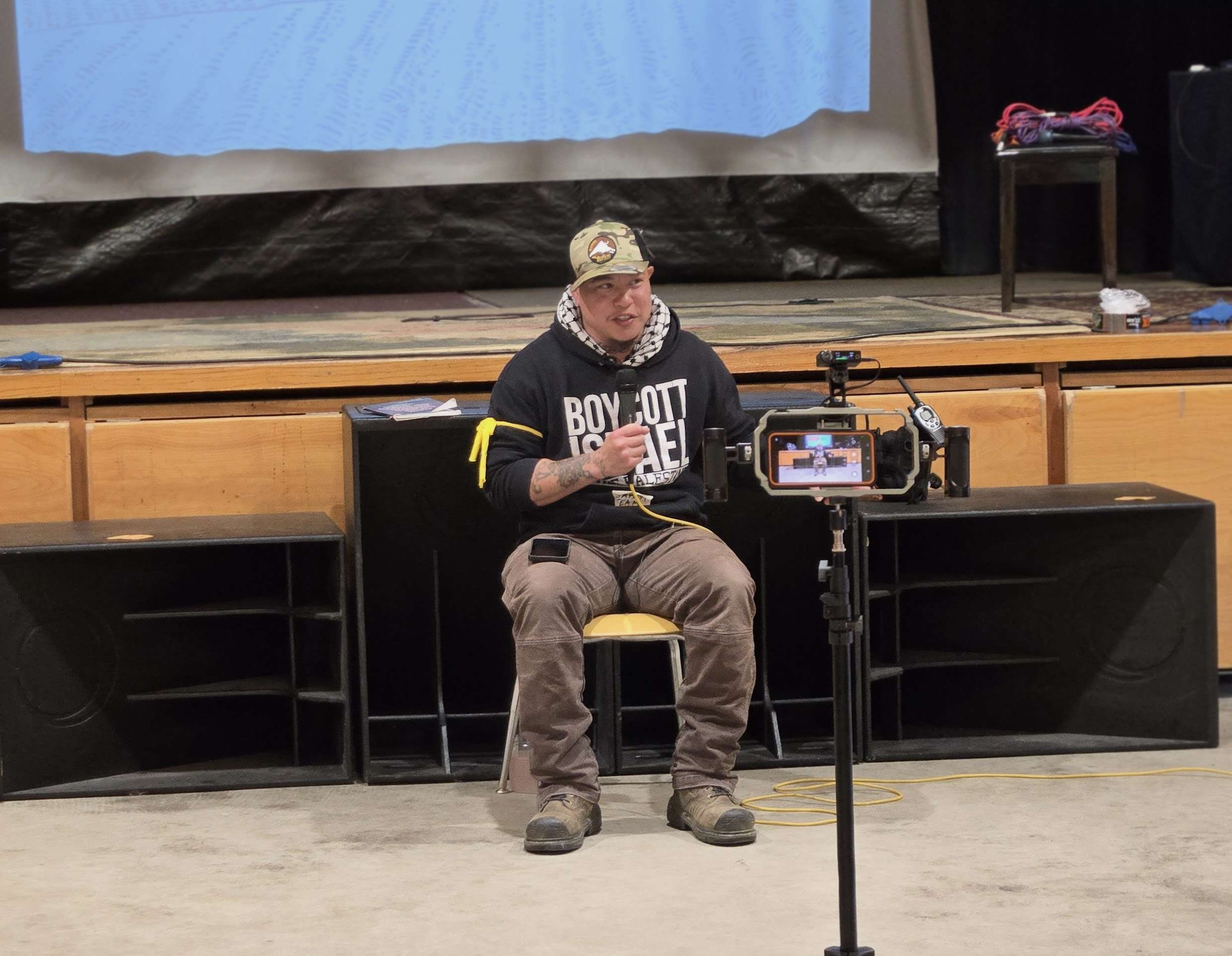 Tighearnan sits and holds a microphone.